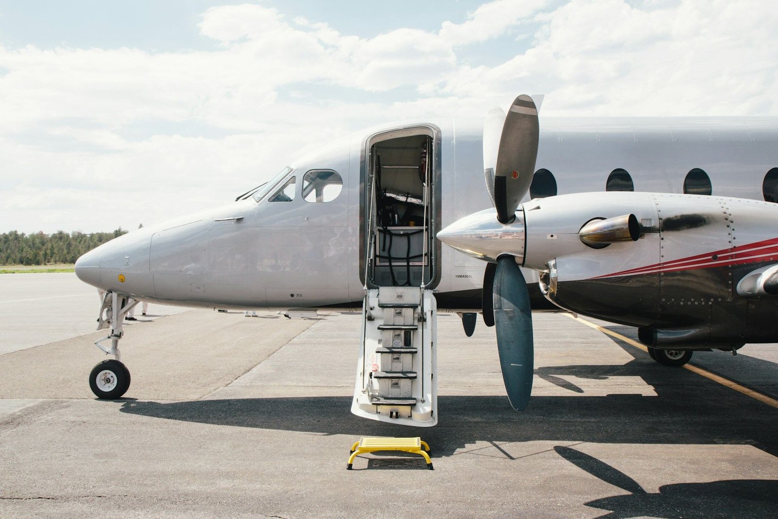 Twin-propeller aircraft parked with its airstair door open