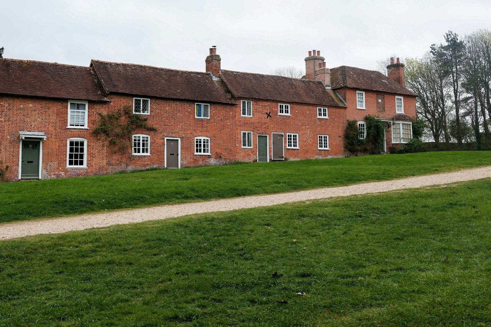 Row of old brick cottages above a sloping lawn