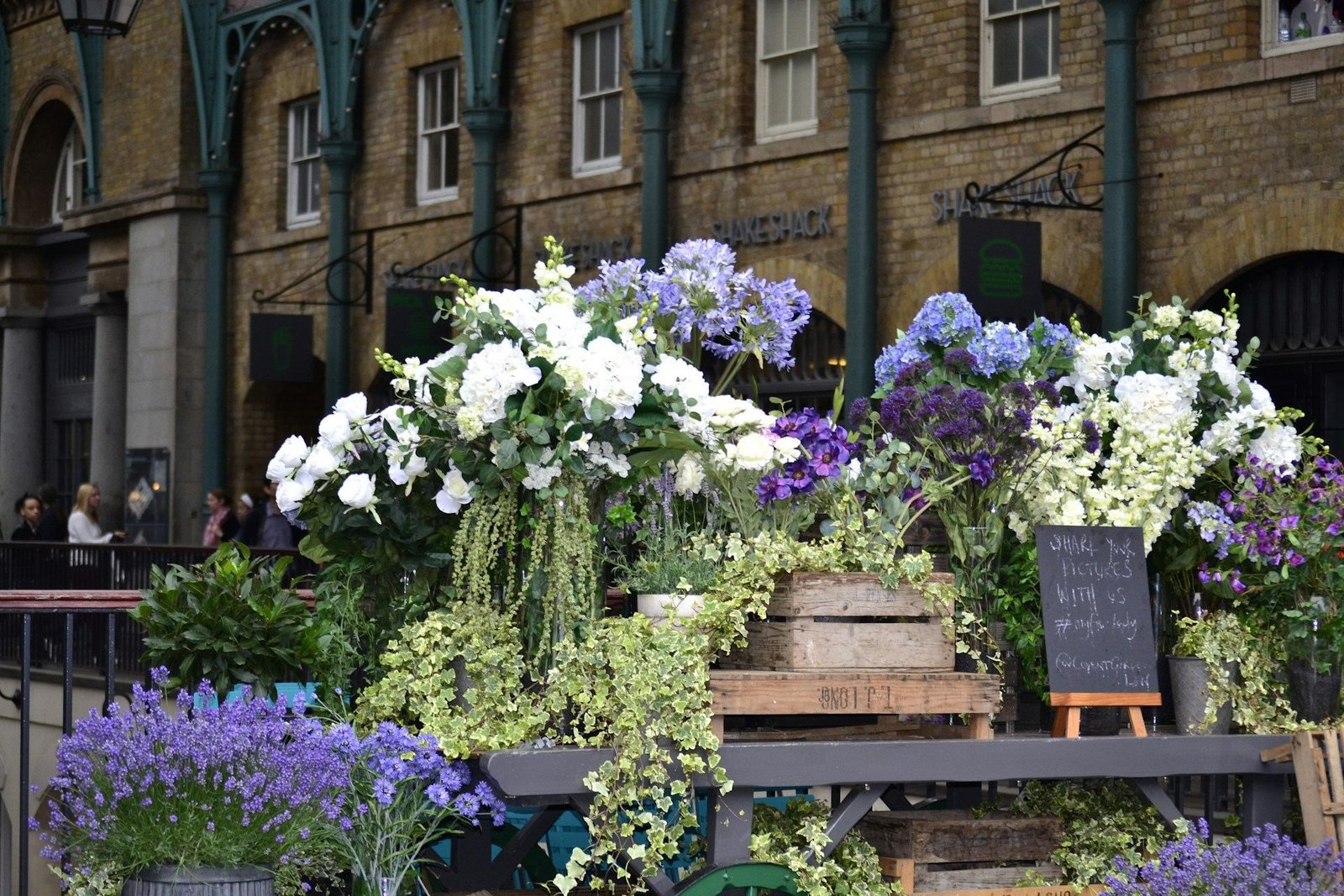 Flower stall with white and purple blooms outside a brick building