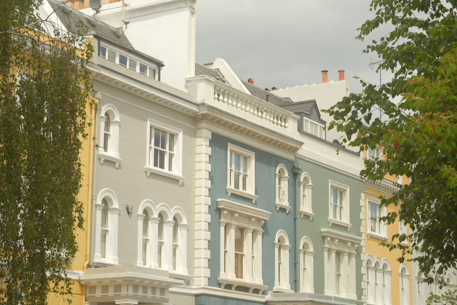 Pastel-painted Victorian houses behind trees