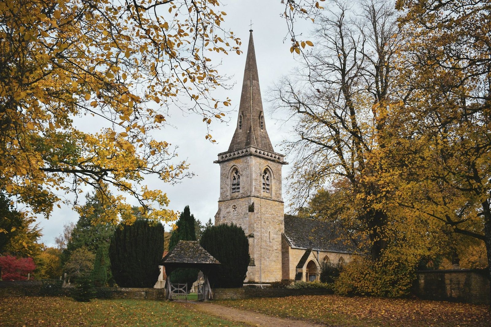 Stone church with a spire among autumn trees