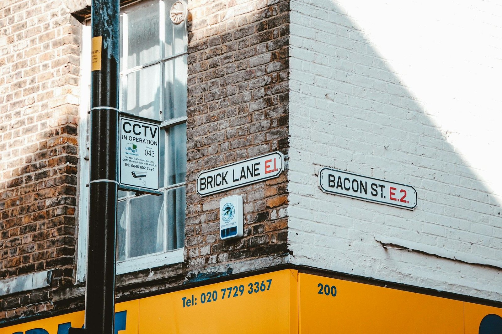 Brick Lane E1 and Bacon Street E2 street signs on a corner