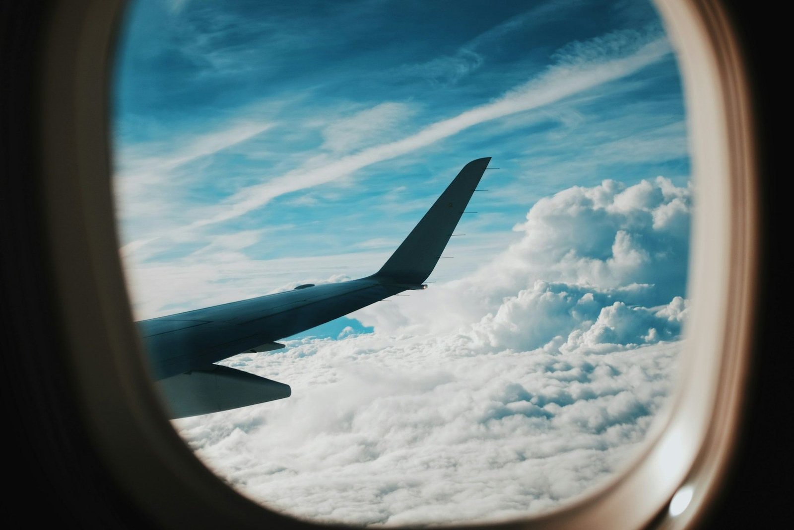 Aircraft wing above the clouds seen through a cabin window