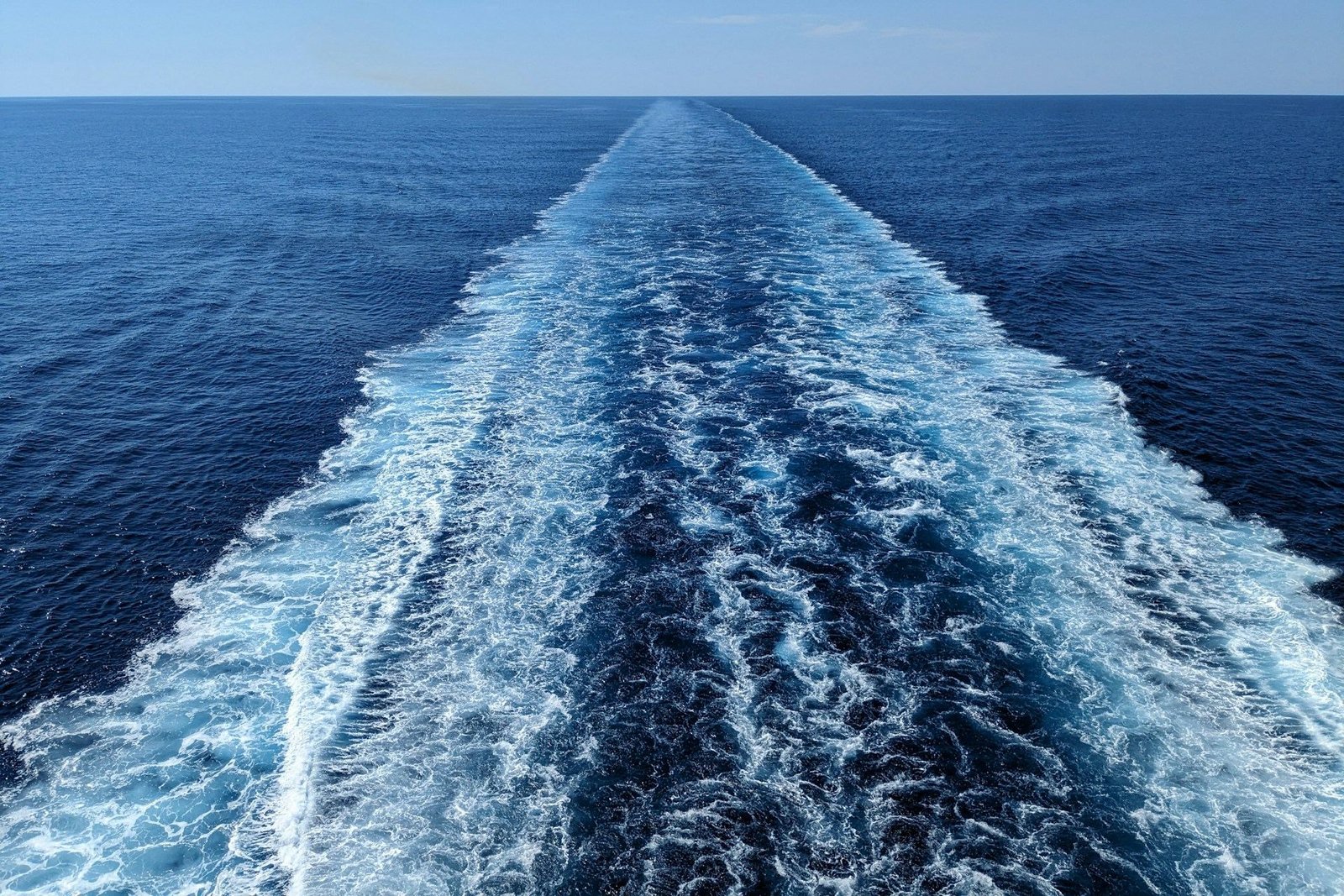 White wake trailing behind a ship on a deep blue sea
