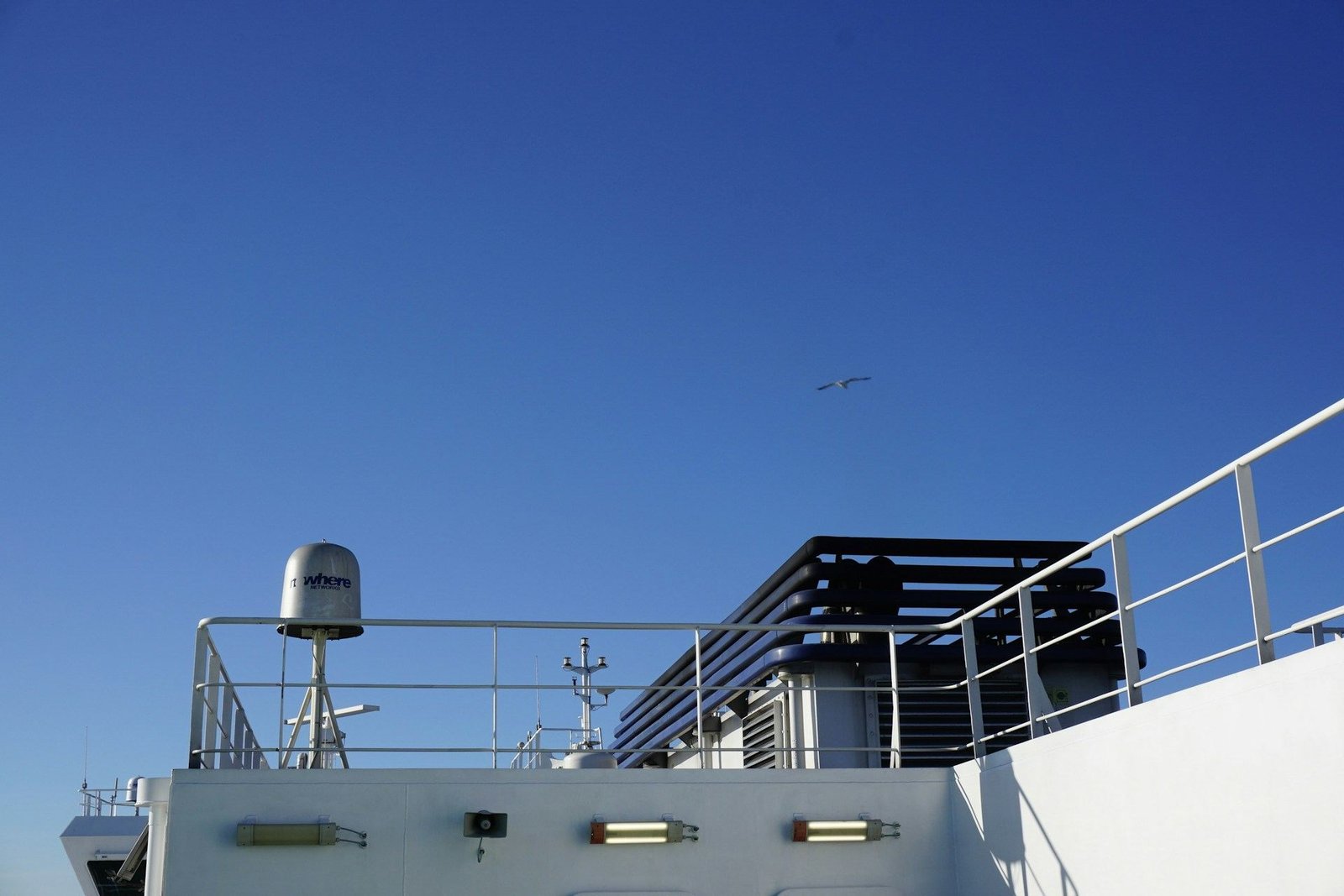 Upper deck and railings of a ferry under a blue sky