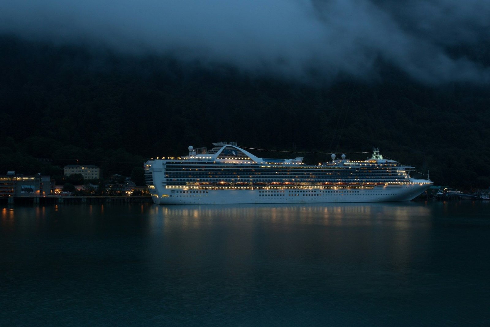 Cruise ship lit up at dusk on calm water