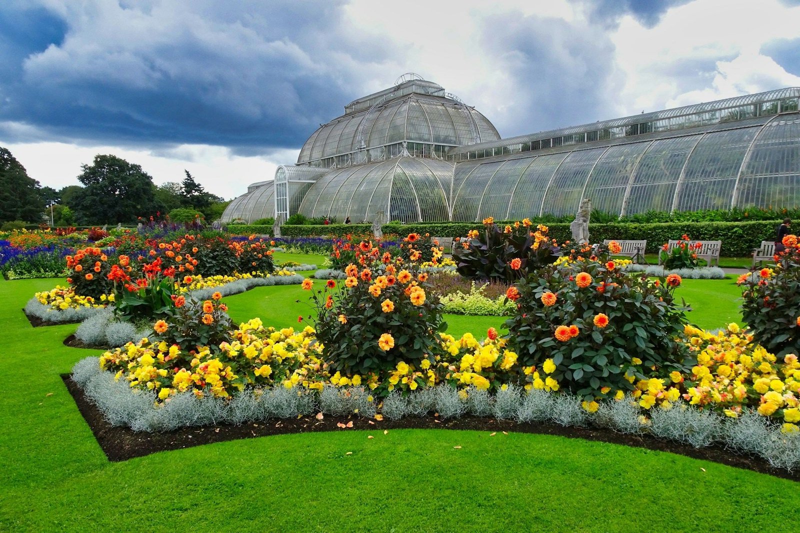 Kew Gardens Palm House behind bright flower beds