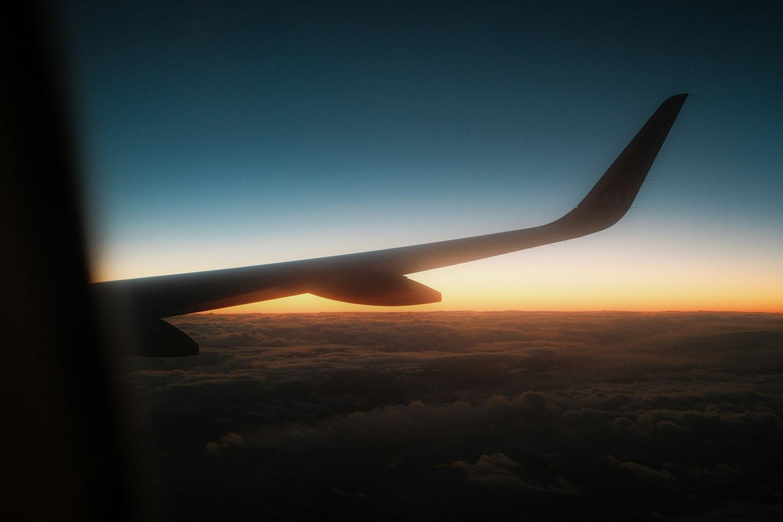 Aircraft wing silhouetted at sunset through a window