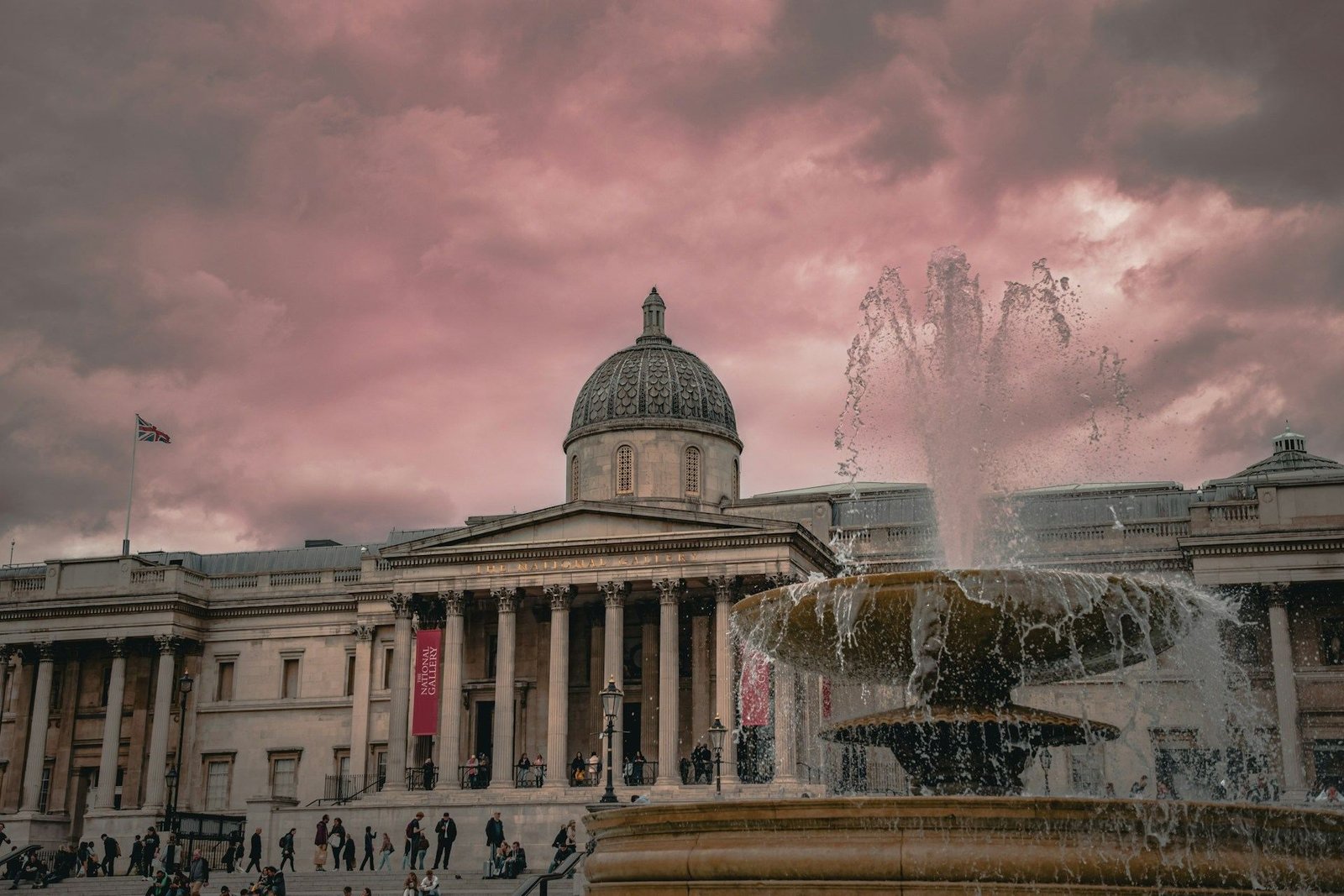 National Gallery and Trafalgar Square fountain under a pink sky