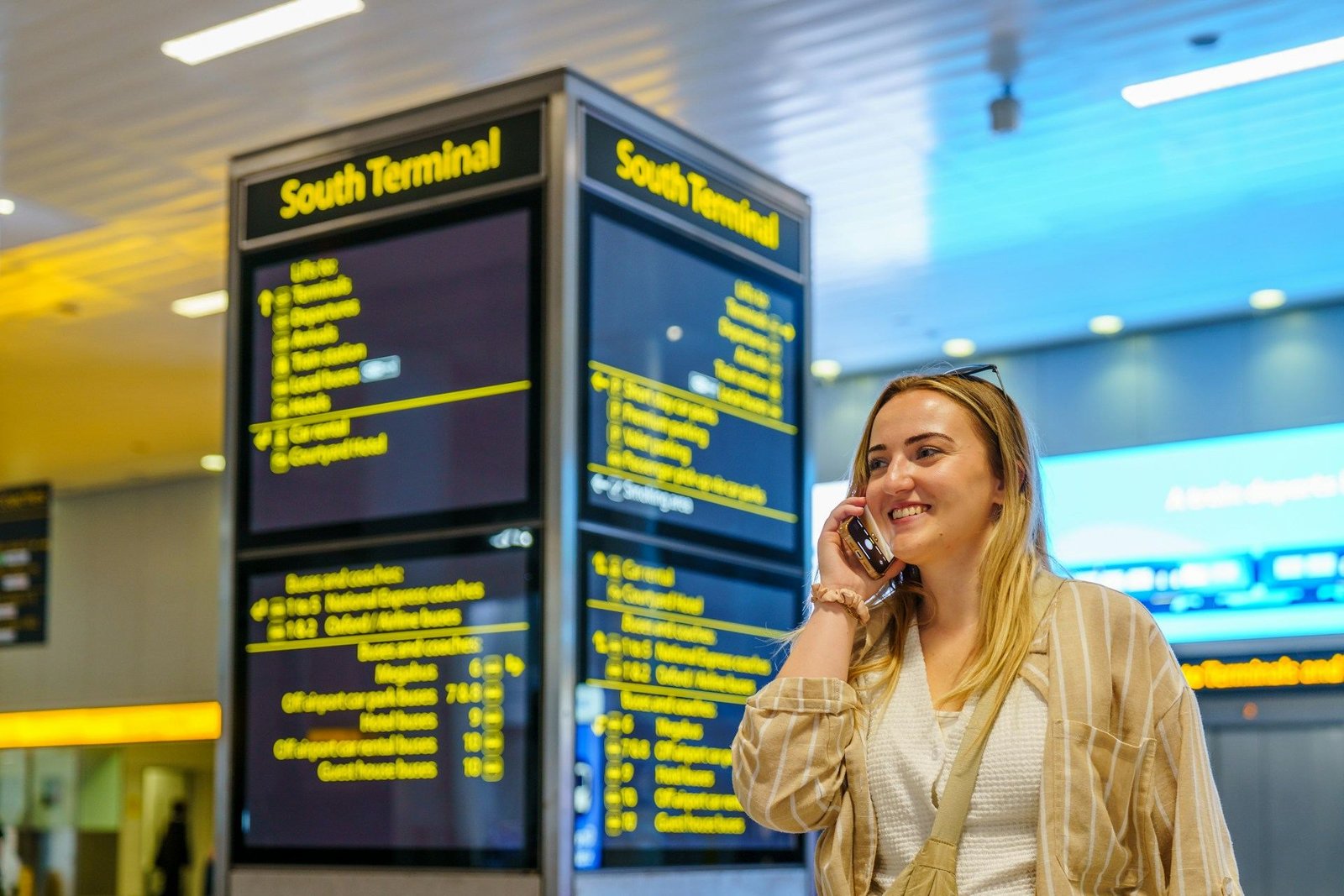 Traveller on a phone call beside South Terminal departure boards