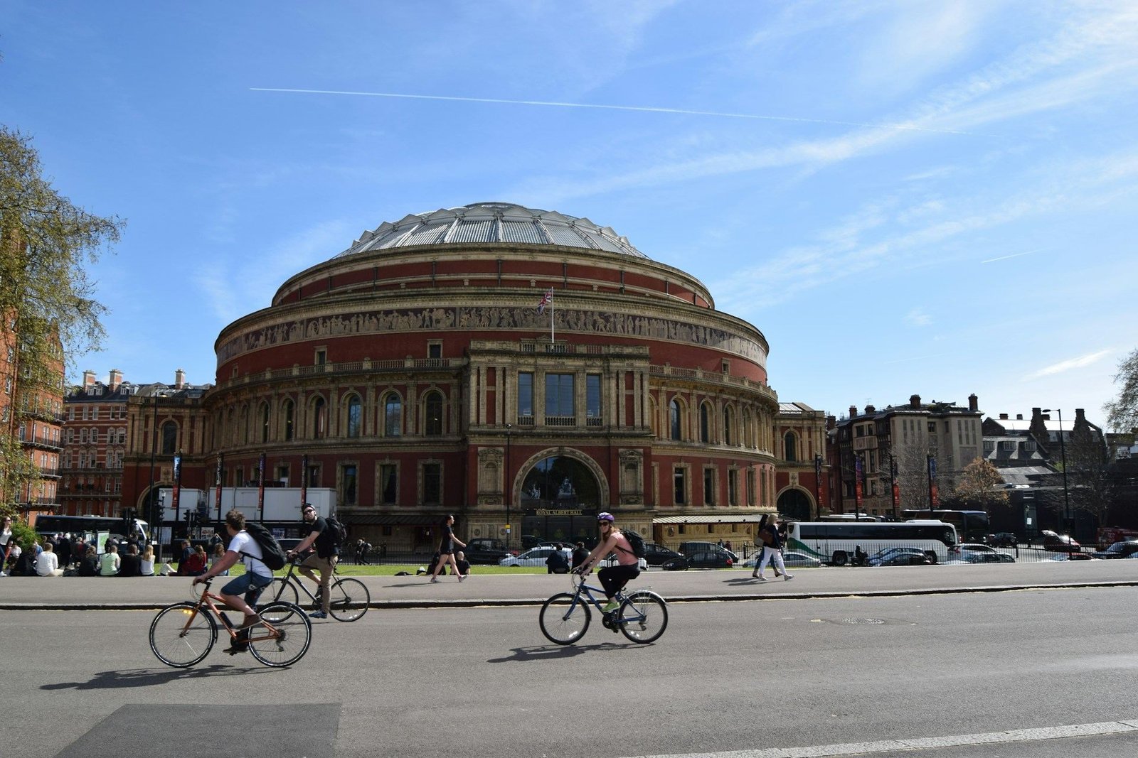 Cyclists passing the Royal Albert Hall on a sunny day